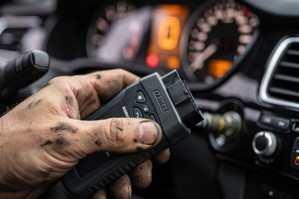 Mechanic plugging an OBD-II scanner into a car's diagnostic port